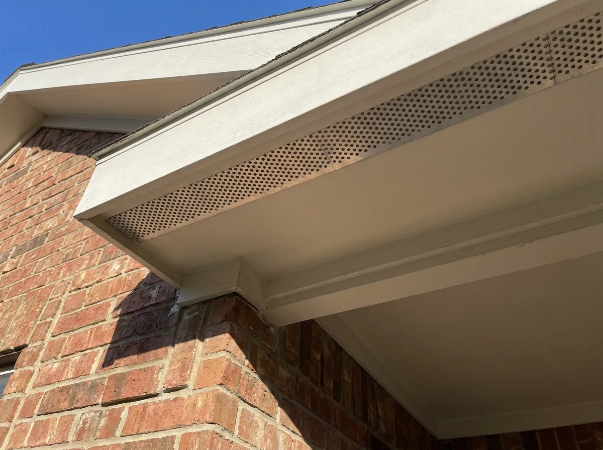 Continuous soffit intake vents being added under the eave of a North Texas home during a roof replacement