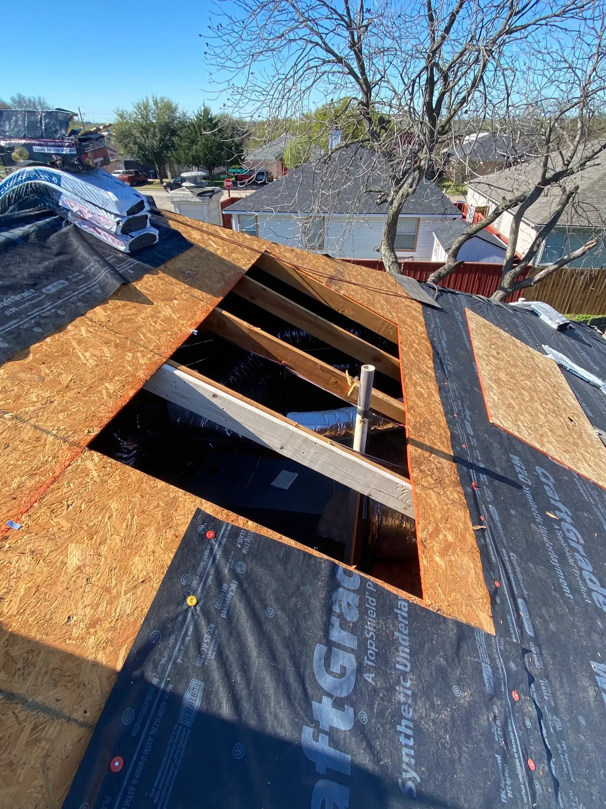 Open hole in a roof deck exposing the rafters below during an emergency repair on a North Texas home
