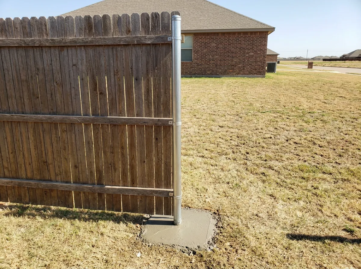 Galvanized steel sleeve post repair installed beside an aging cedar fence post at a North Texas home