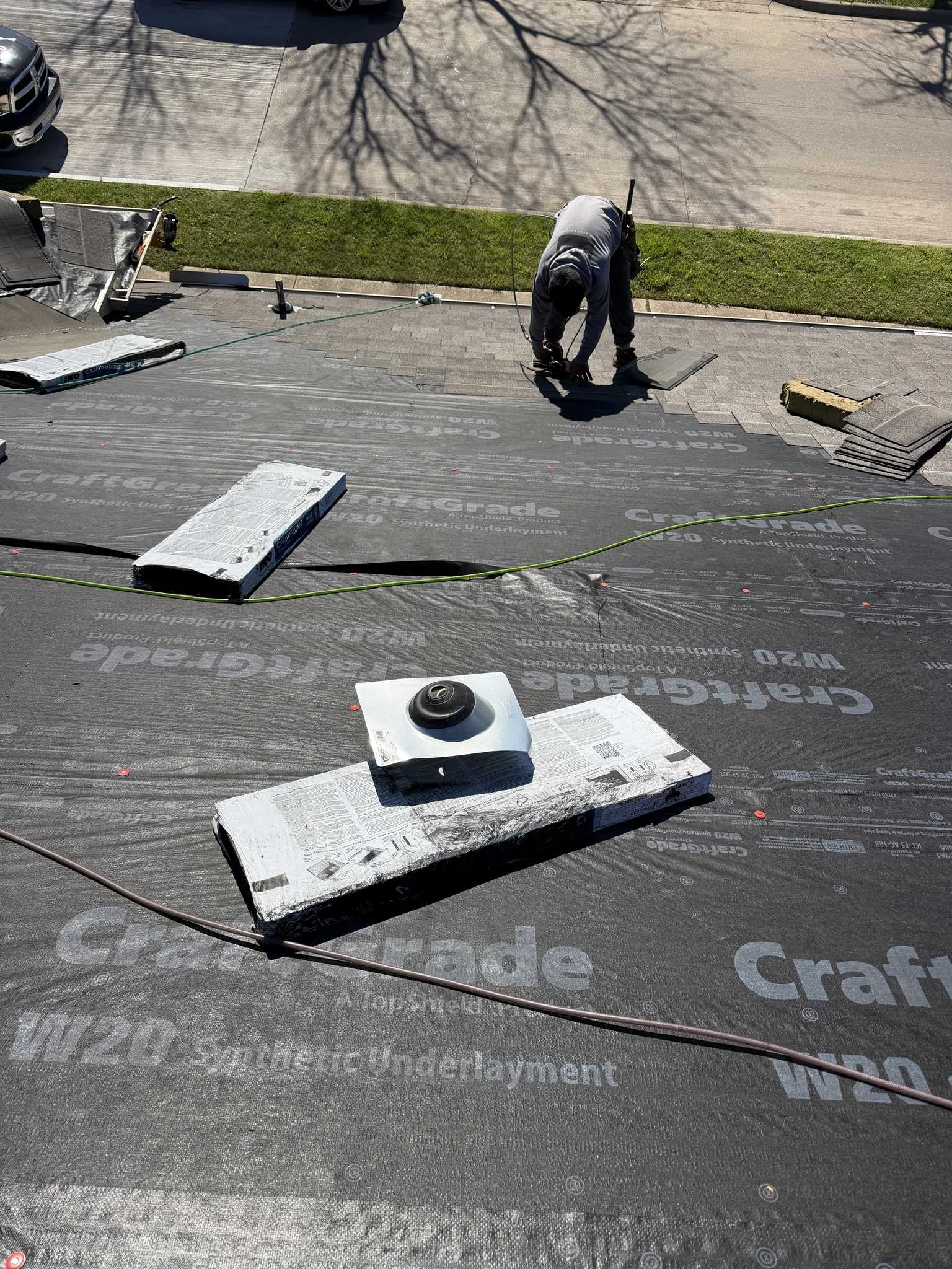 New synthetic underlayment going down over the exposed roof deck after a full tear-off on a North Texas home