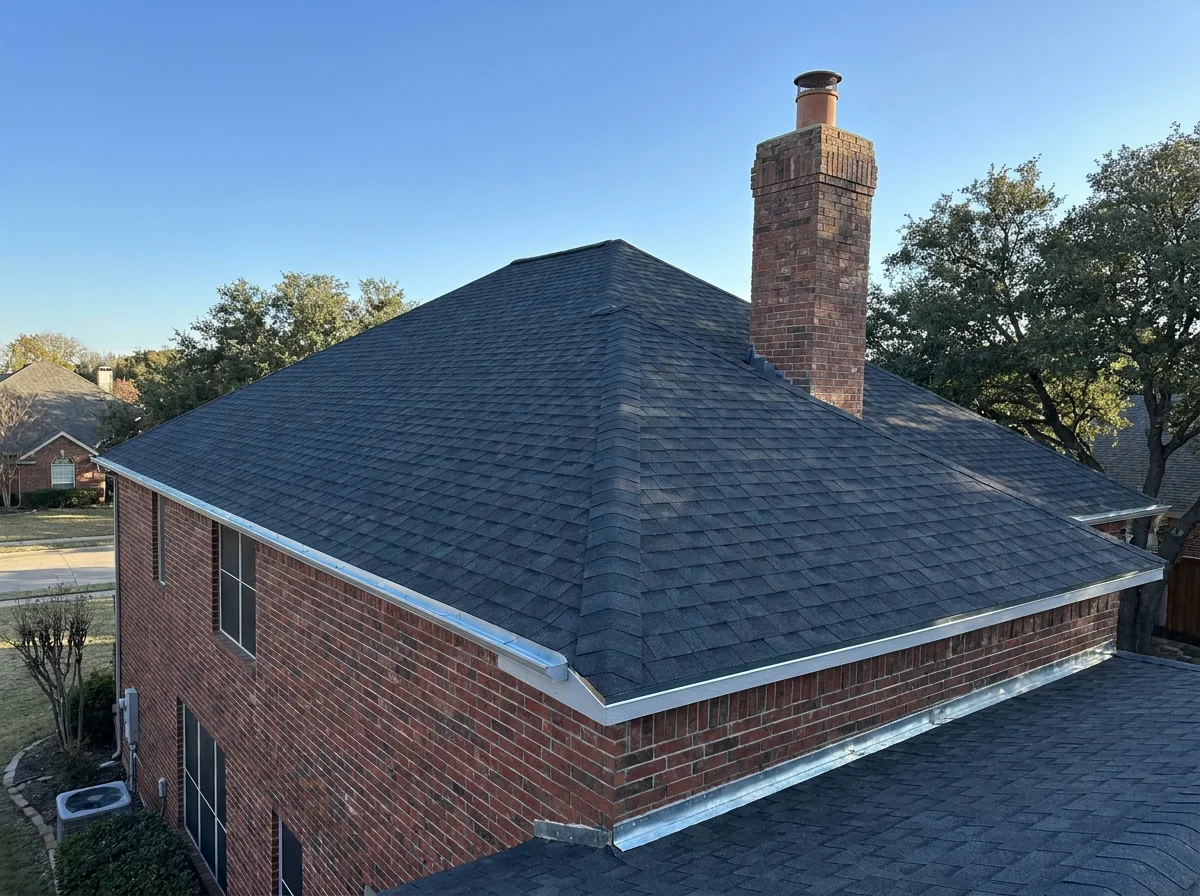 Finished charcoal architectural asphalt shingle roof with a brick chimney on a North Texas home after a full replacement