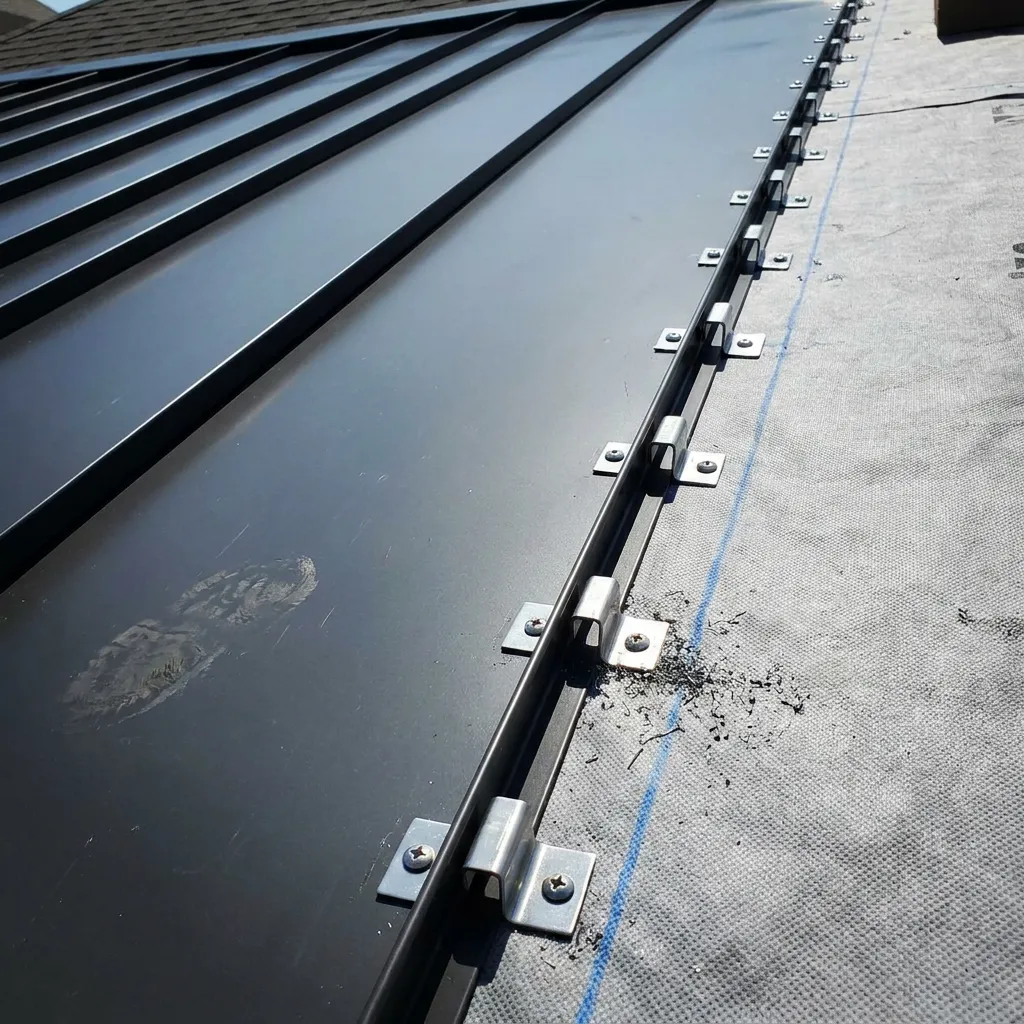 Close-up of a concealed clip fastener locking a standing seam metal roof panel