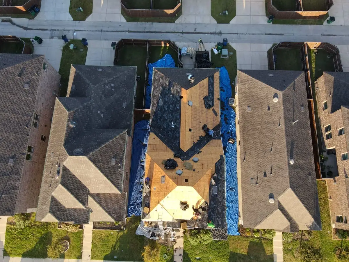 Top-down drone view of a full tear-off with the roof deck completely exposed during a Roof Raiders re-roof on a North Texas home